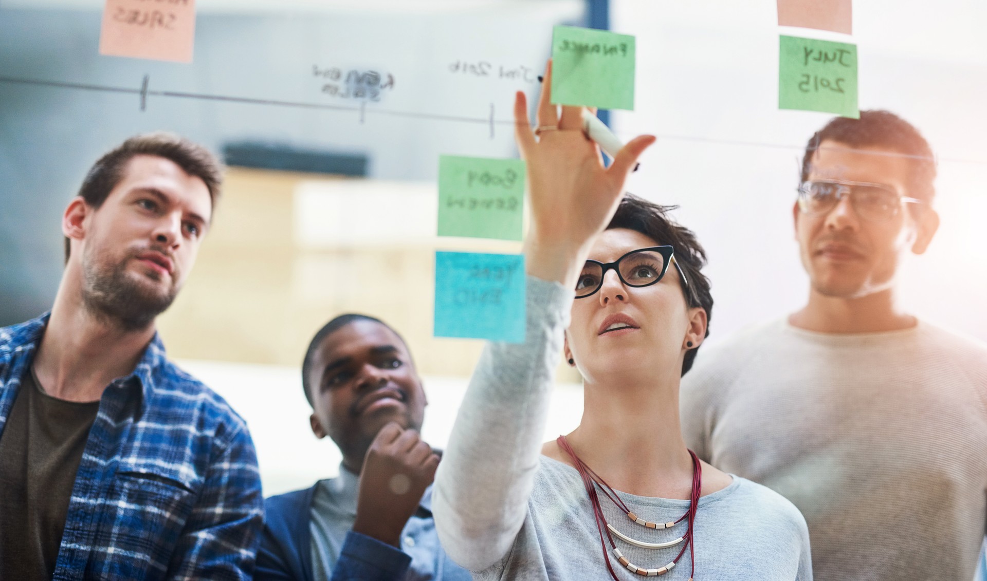 Woman leader, team and sticky notes on glass for timeline, strategy and brainstorming in workshop. Female speaker, presentation and group training in boardroom for idea, collaboration and information