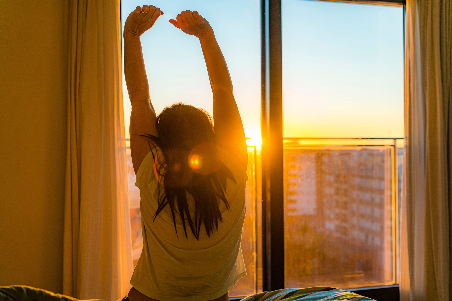 Woman sitting in bed stretching in the morning