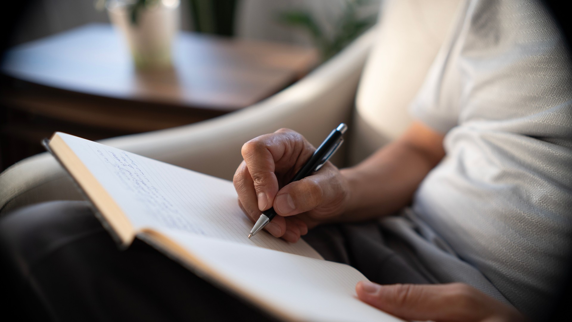 Close-up senior man hand writing in notebook at home